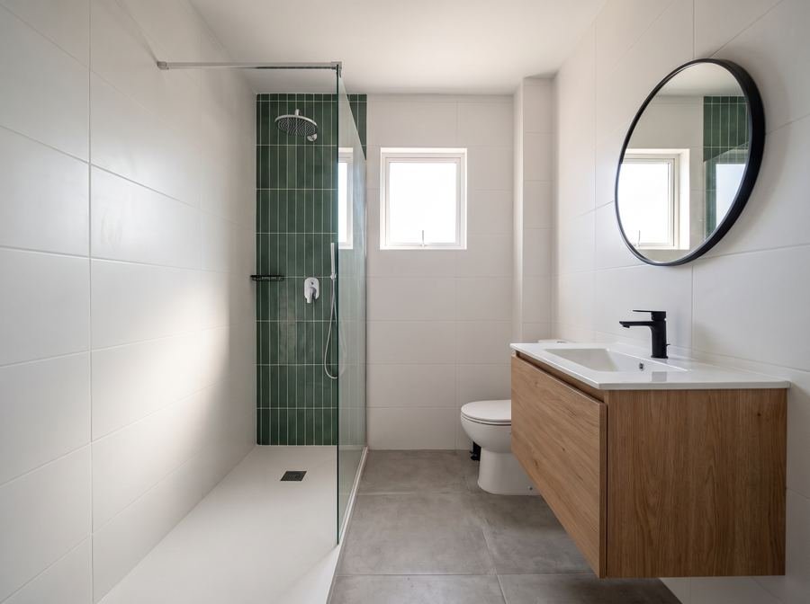 Baño reformado con ducha de vidrio y mueble de roble